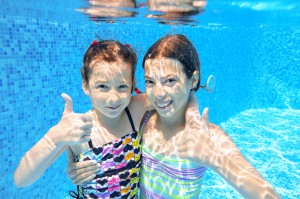 Happy active kids swim in pool and play underwater, girls diving